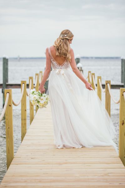 Bride walking on a pier with a bouquet of flowers in hand