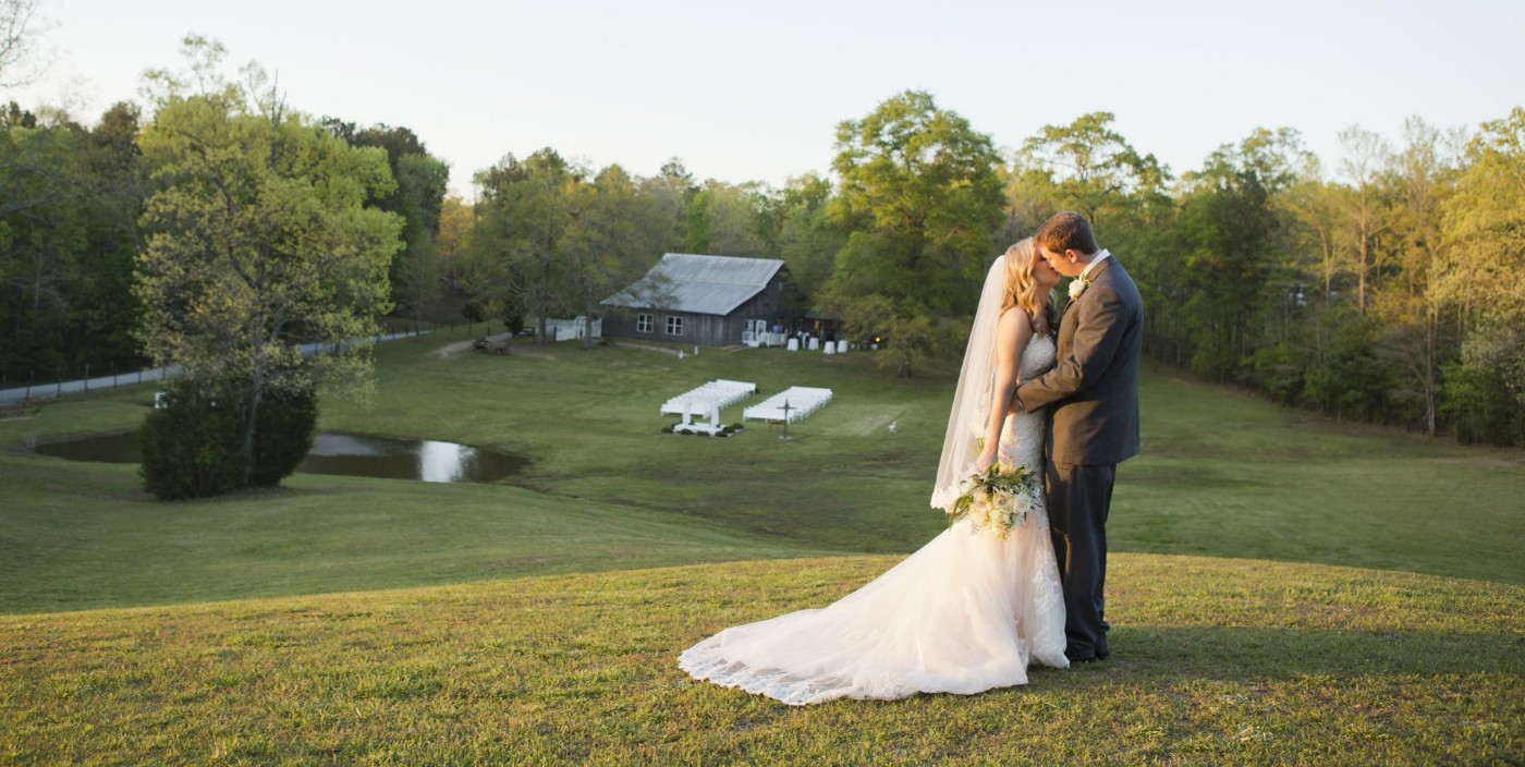 An Image of a bride and groom kissing on a hill
