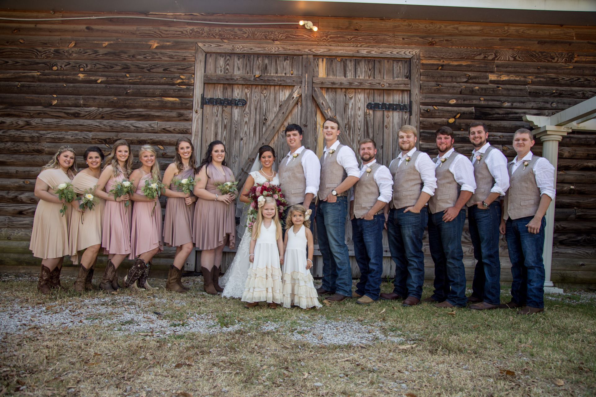 An image of a bridal party posing for a picture in front of a barn