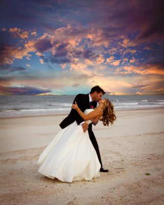 Groom dipping bride for a kiss on the beach